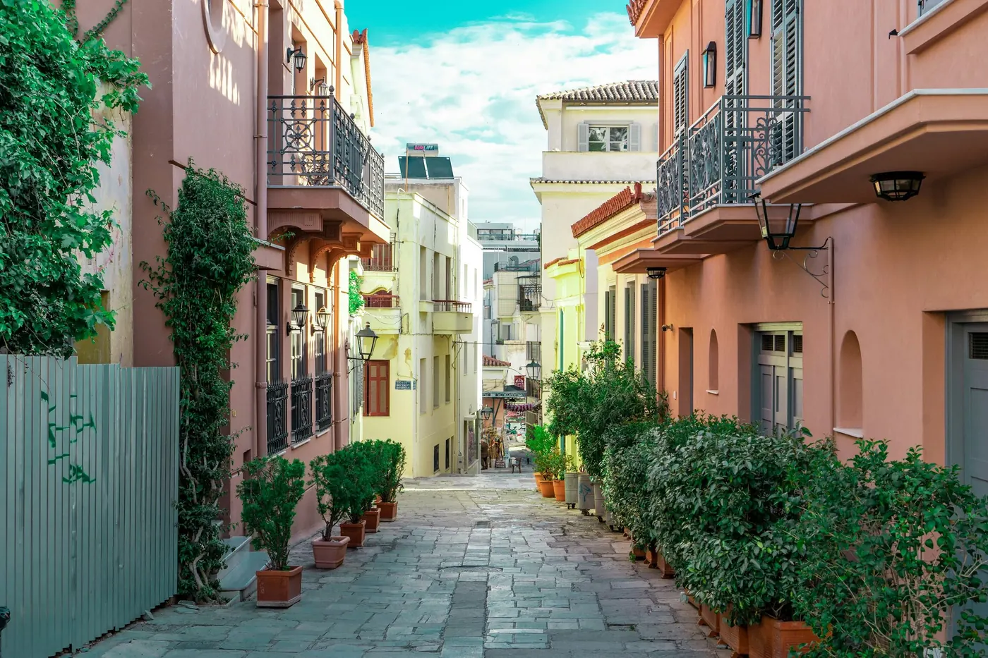 A leafy pedestrian lane between colorful buildings in Athens